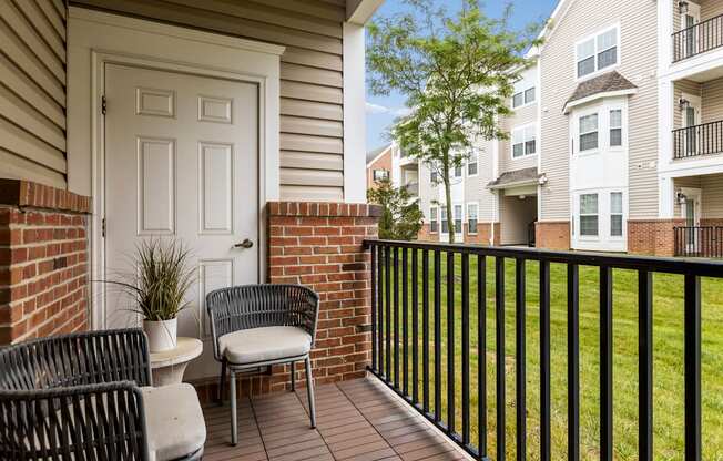 A patio with a table and chairs overlooking a grassy area.