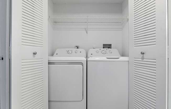 a white laundry room with two washes and a dryer