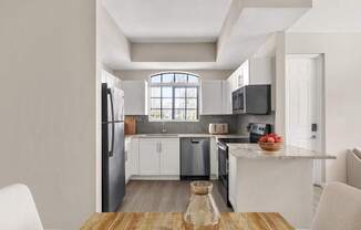 A modern kitchen with white cabinets and a wooden table.