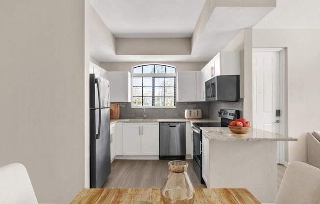 A modern kitchen with white cabinets and a wooden table.