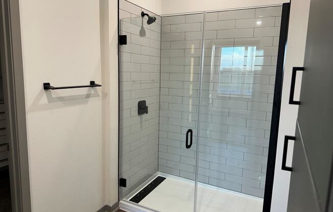 a white tiled shower in a bathroom with a glass door at The Depot, Missouri, 64083