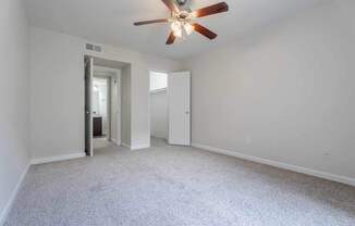 A room with a ceiling fan and carpeted floor.