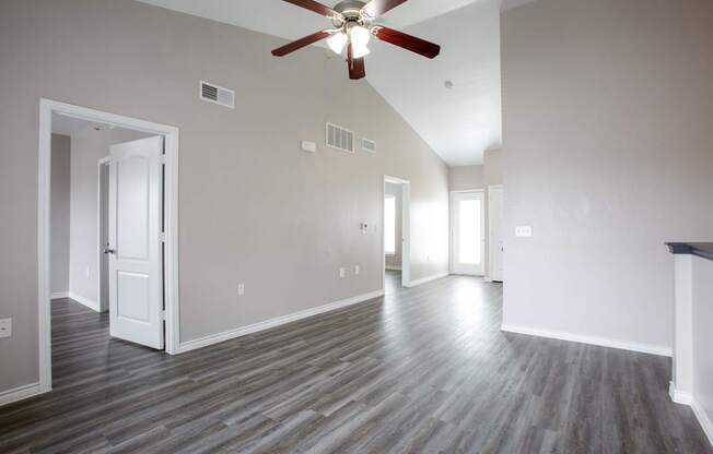 A room with a ceiling fan and wood flooring.