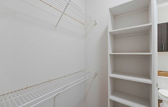 a walk in closet with shelves and a toilet in it