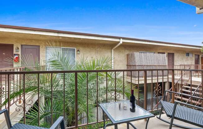 a balcony with a table and chairs and a bottle of wine on it