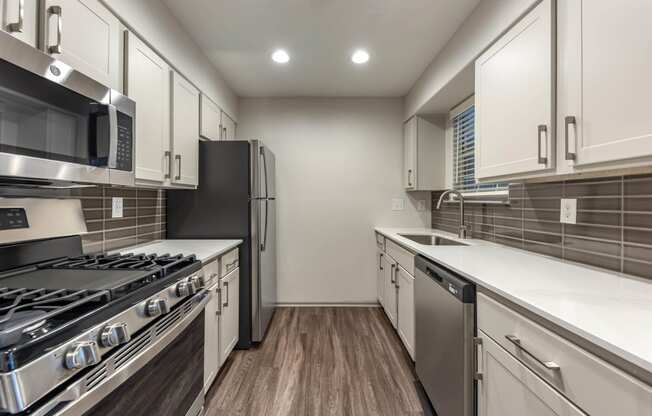 a modern kitchen with stainless steel appliances and white cabinets