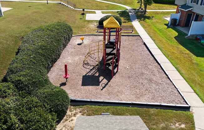 A playground with a red swing set and a yellow slide.