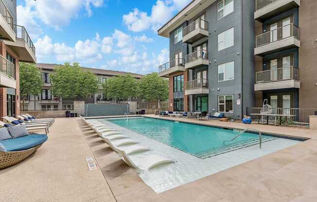 A large swimming pool is surrounded by apartment buildings.
