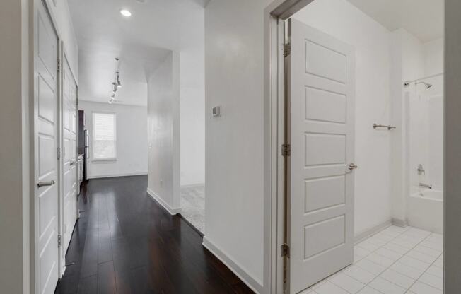 a renovated living room and kitchen with white walls and wood floors