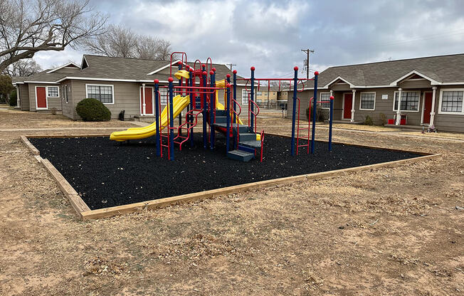 a playground with a slide in front of a row of houses