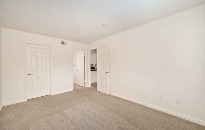 a bedroom with white walls and carpet and white doors