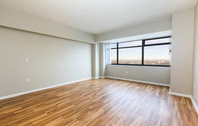 an empty living room with wood floors and a window at Apartments at Denver Place, Denver, CO