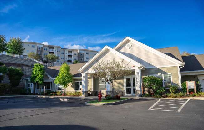 Exterior view of clubhouse and leasing office with apartment building visible on hill behind office at Summit Place apartments in Methuen, MA.