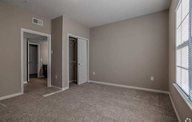 A room with a carpeted floor and two doors leading to other rooms.at The Residences at Akita Lane, Canal Winchester, OH 43110