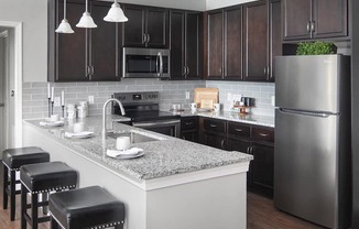 a kitchen with a marble counter top and a stainless steel refrigerator