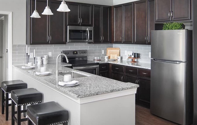 a kitchen with a marble counter top and a stainless steel refrigerator