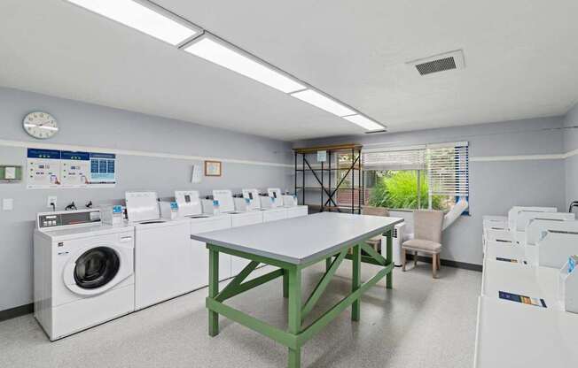 A laundry room with a table, chairs, and washing machines.
