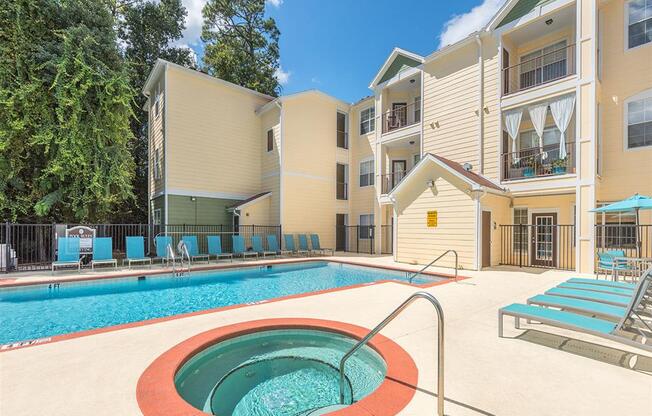 Hot tub spa next to resort-style swimming pool and sundeck at Evergreens at Mahan apartments in Tallahassee, FL