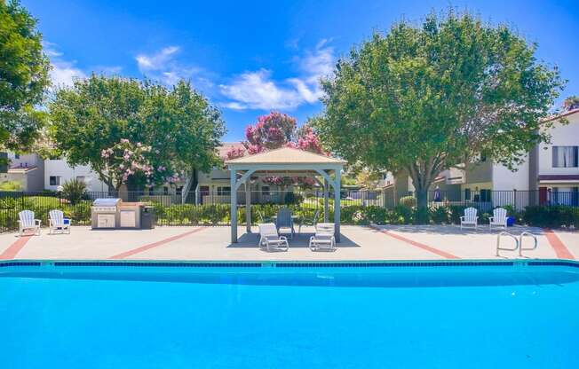 a swimming pool with chairs and a gazebo in front of a building