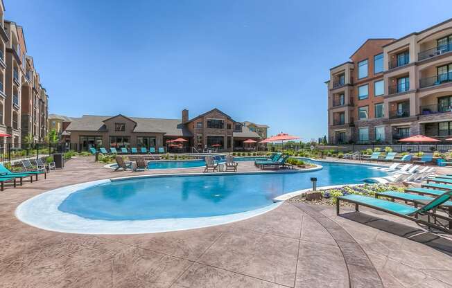 a swimming pool with chaise lounge chairs and a resort style building in the background