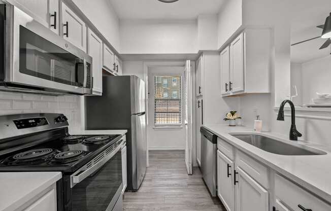 an empty kitchen with white cabinets and stainless steel appliances