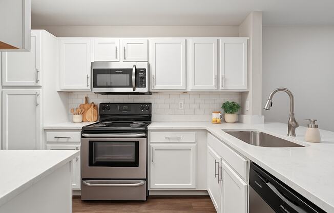 A modern kitchen with white cabinets and a black stove top oven.