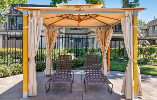 a patio with a gazebo and two chairs