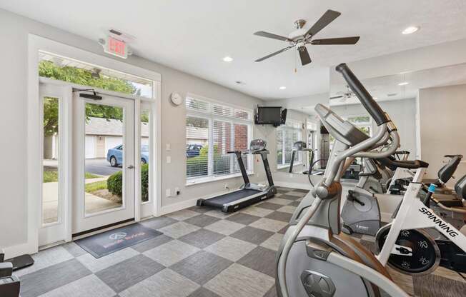 A Spinning bike is in a well lit gym with a checkerboard floor.