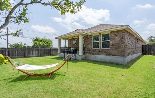 a backyard with a hammock and a brick house