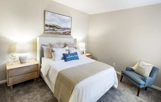 a bedroom with a white bed and a blue chair