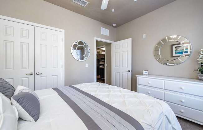 A bedroom with a large bed, two dressers, and a mirror on the wall.