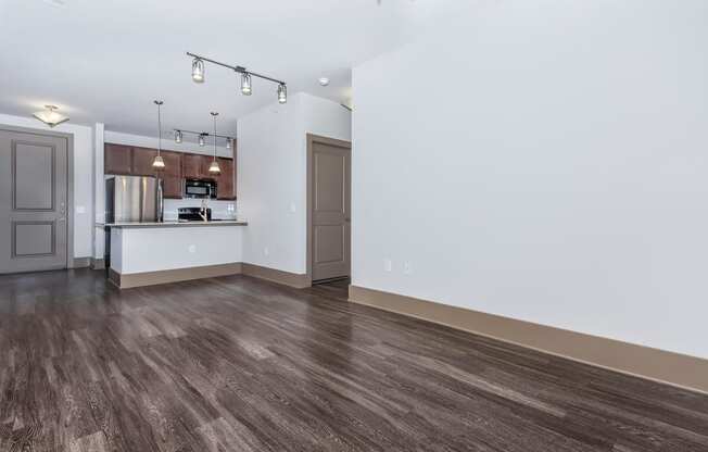 a living room and kitchen with white walls and wood floors