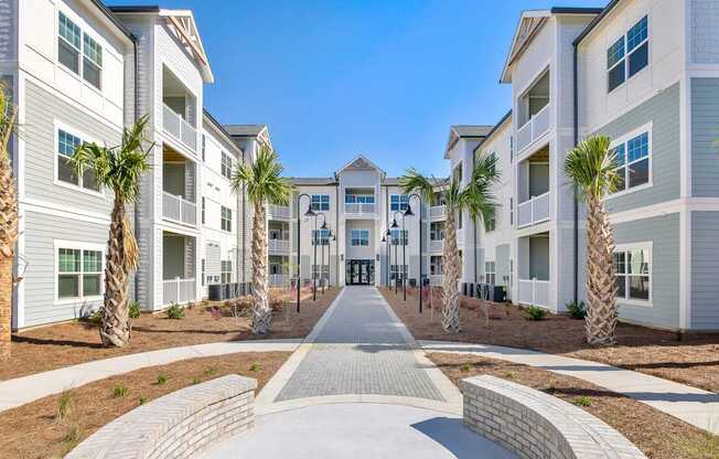 A row of white apartment buildings with a pathway in the middle.