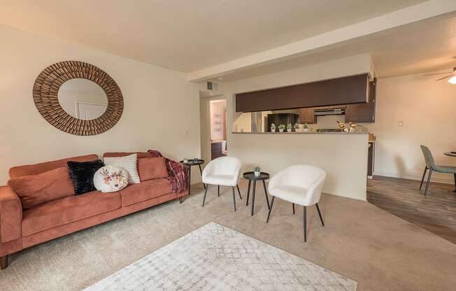 Model living room with a brown couch and a round mirror on the wall at Pheasant Pointe Apartments, California, 95833