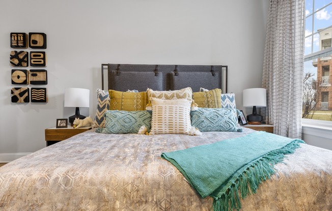 A bed with a gold comforter and a green throw.