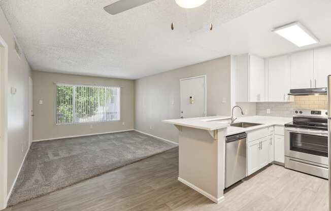 an empty kitchen and living room with white cabinets and a window