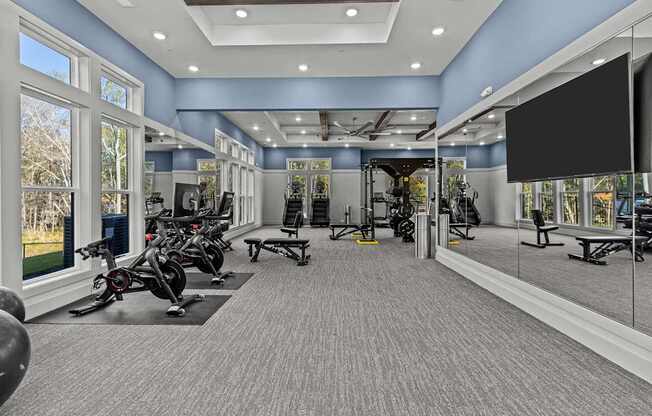 A spacious gym with a variety of exercise equipment and a large mirror on the wall.