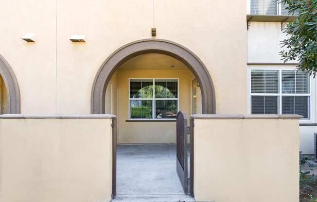 an arched doorway to an apartment building with a tree in the background