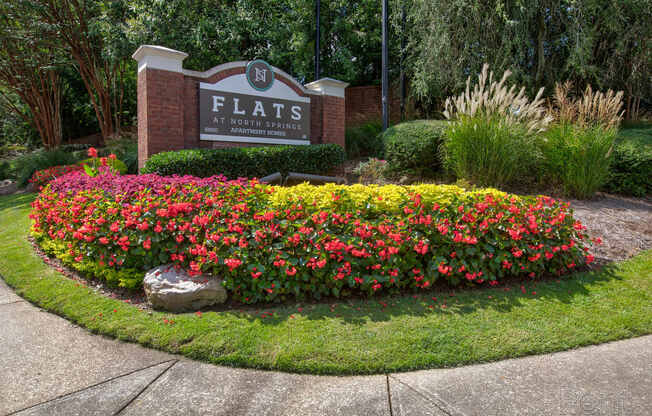 a flower garden in front of a sign for flats at woodbury