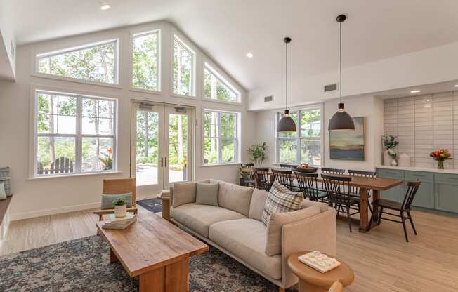 an open concept living room and dining room with large windows and a vaulted ceiling