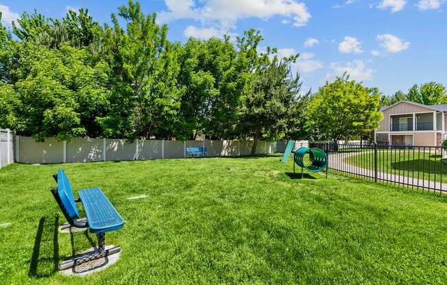 A green lawn with a blue chair and a green bench.
