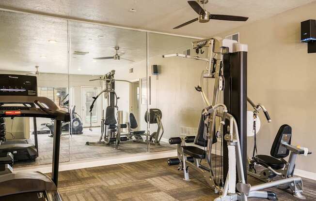 A gym with a mirrored wall and a variety of equipment.