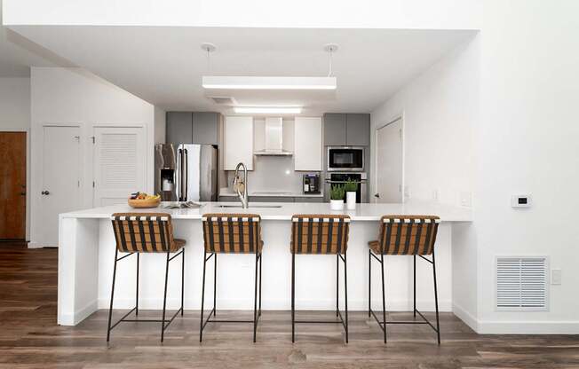 A modern kitchen with a white island and bar stools.