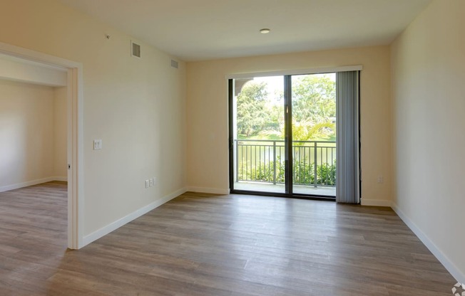 an empty living room with a sliding glass door leading to a balcony