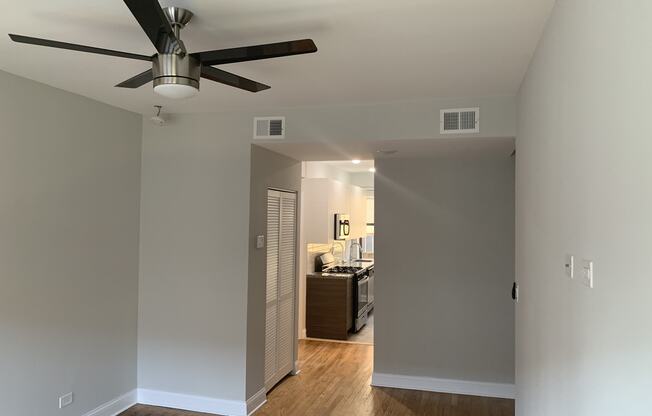 a living room with a ceiling fan and a hallway to a kitchen