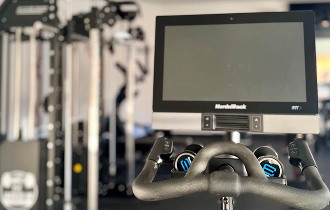 A stationary exercise bike with a monitor attached to the handlebars.