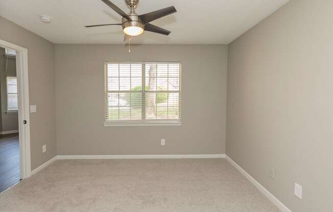 empty apartment bedroom with carpeting and a ceiling fan