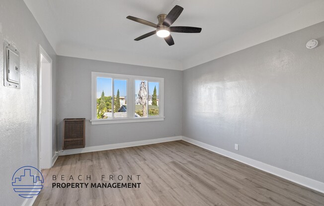 an empty living room with a ceiling fan and a window