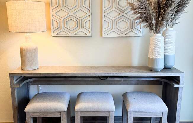 a console table with three stools and two paintings on the wall