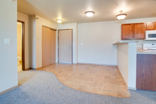 an empty living room and kitchen with a microwave and a sink